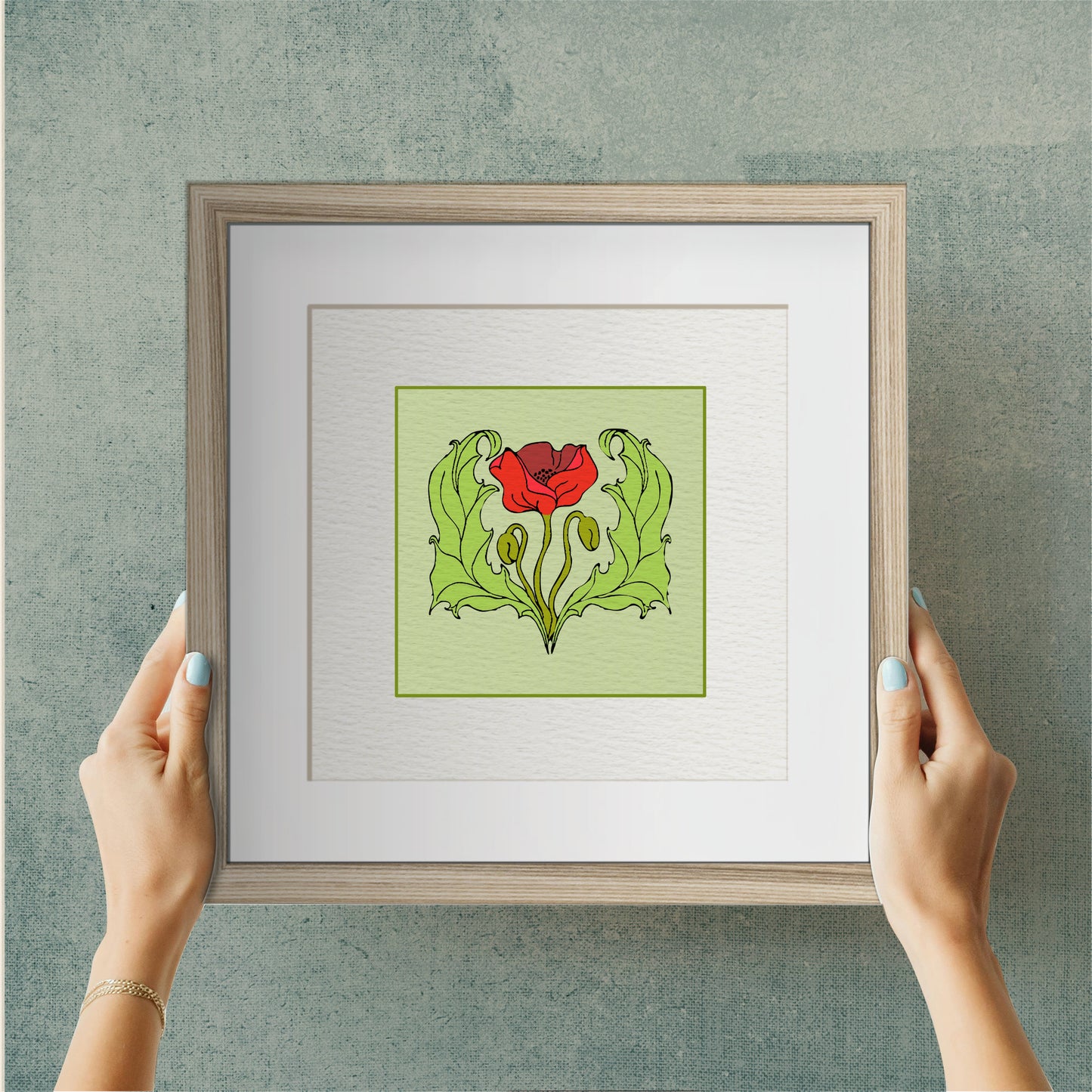 Person holding a Framed Art Print - Poppy featuring a red poppy flower with green leaves on a light background, surrounded by a natural wooden frame.