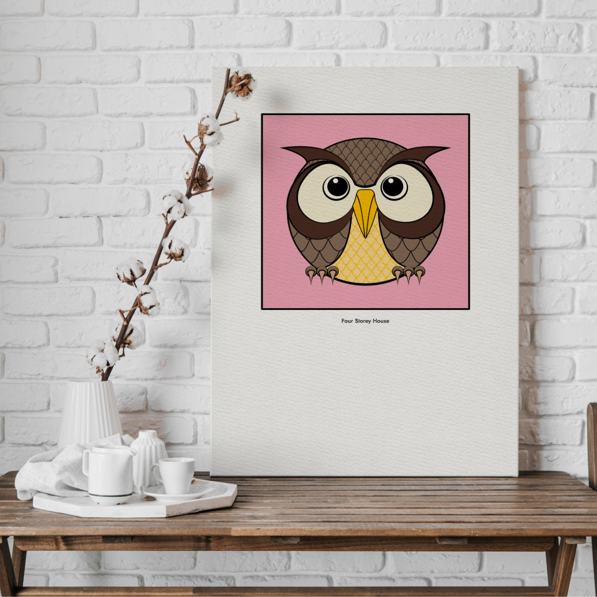 Original A2 Art Print - Owl featuring a stylized owl illustration with neutral tones and yellow accents on a soft pink background, displayed against a white brick wall.