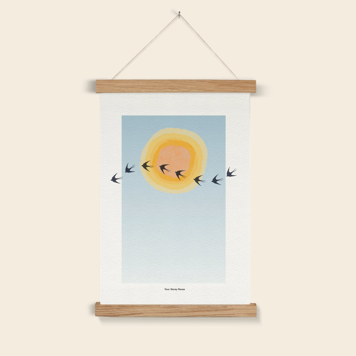 Poster with a sun and birds design on a wooden frame against a beige wall